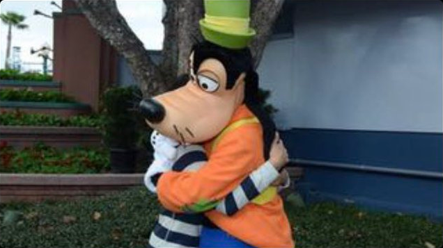 A normally dressed human person hugging a Goofy mascot
